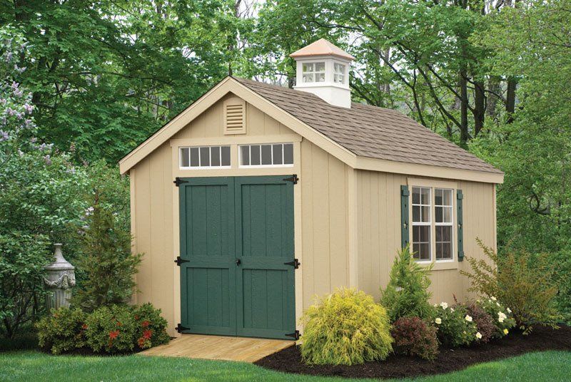 A shed with green doors and a chimney on top of it