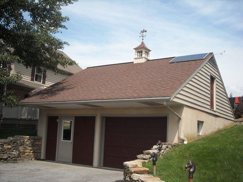A brown garage with a cupola on top of it