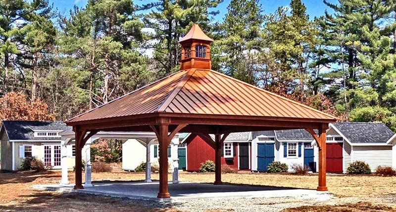A gazebo with a copper roof is in front of a house.