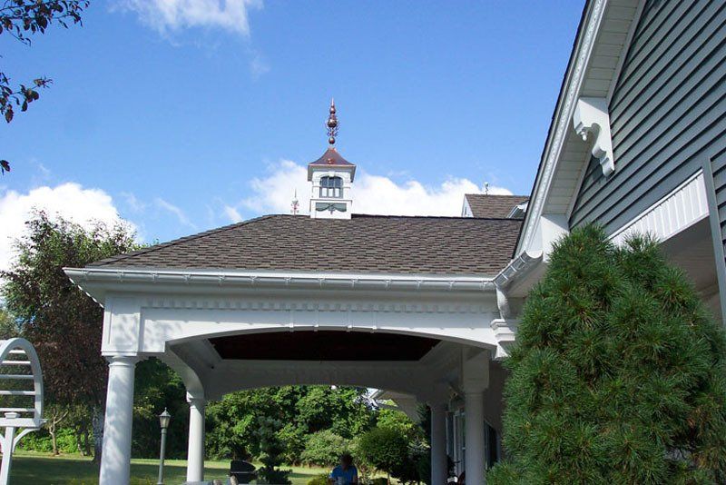 A white house with a roof that has a weather vane on top of it