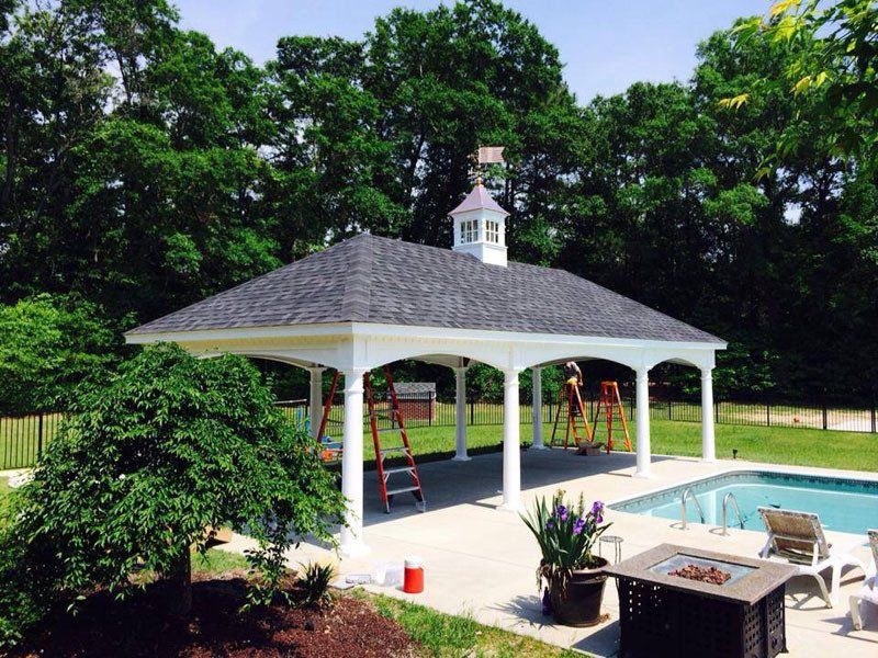 A gazebo with a chimney on top of it next to a swimming pool