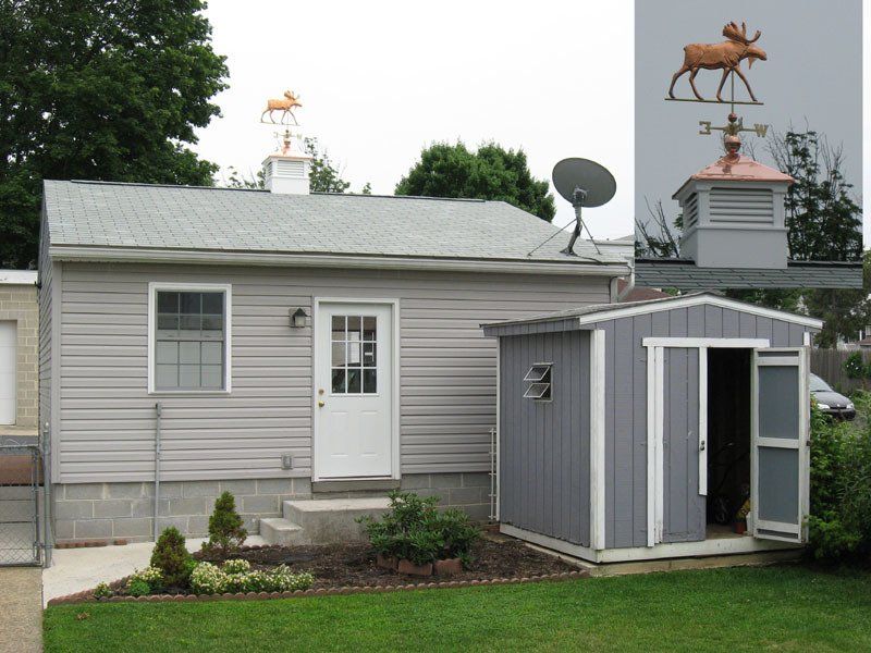 A house with a moose weather vane on top of it