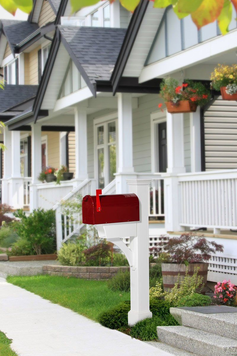 A red mailbox is in front of a white house