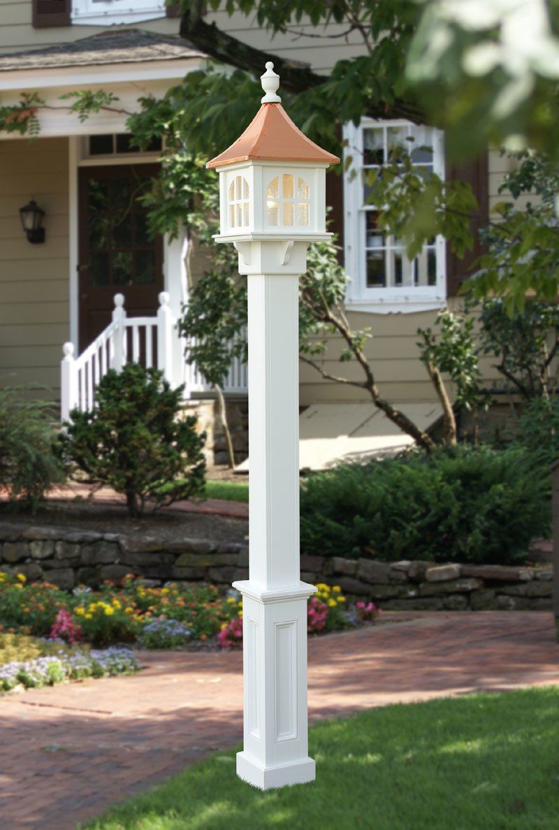 A white pole with a light on top of it in front of a house