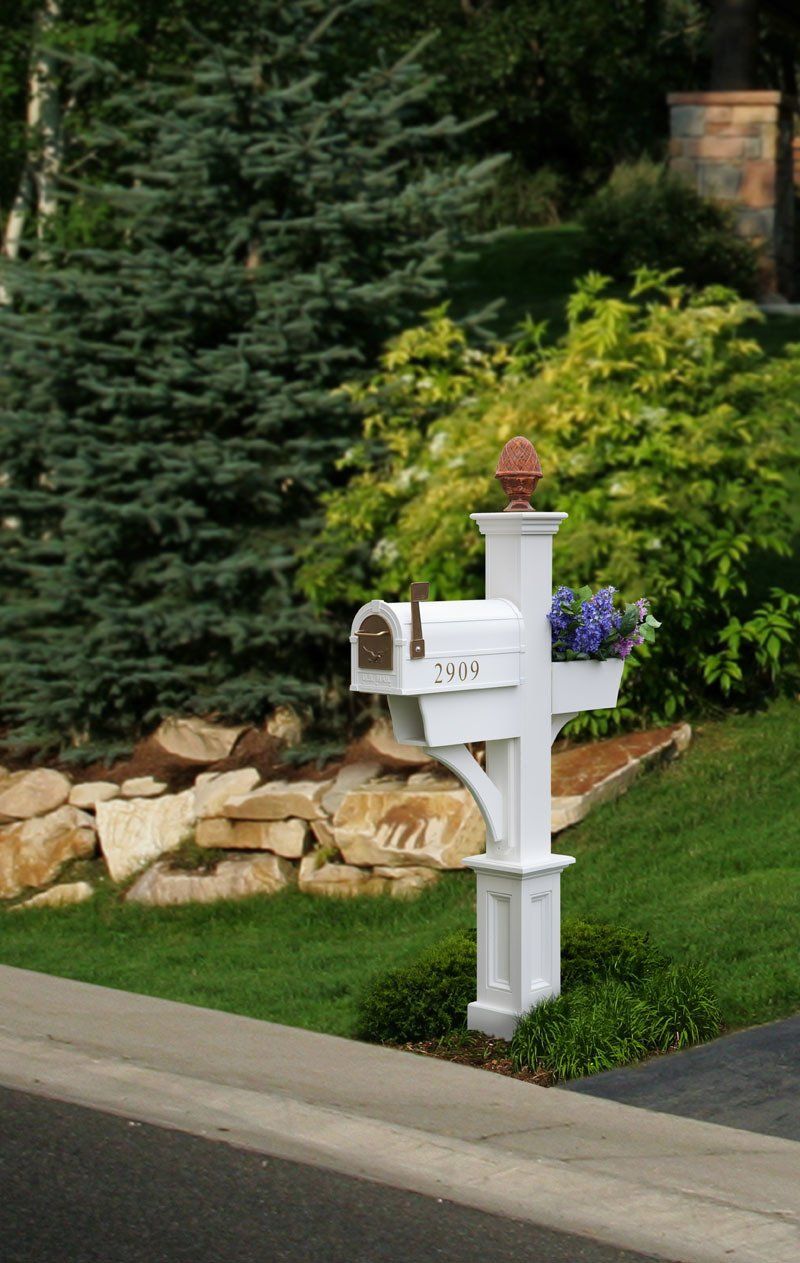 A white mailbox with flowers in it is on the side of the road.