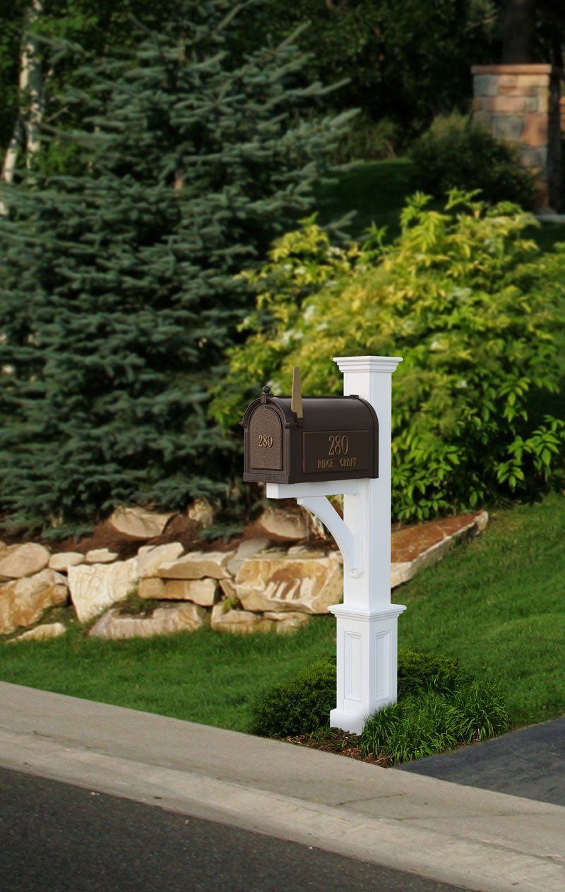 A mailbox is sitting on the side of the road next to a lush green yard.