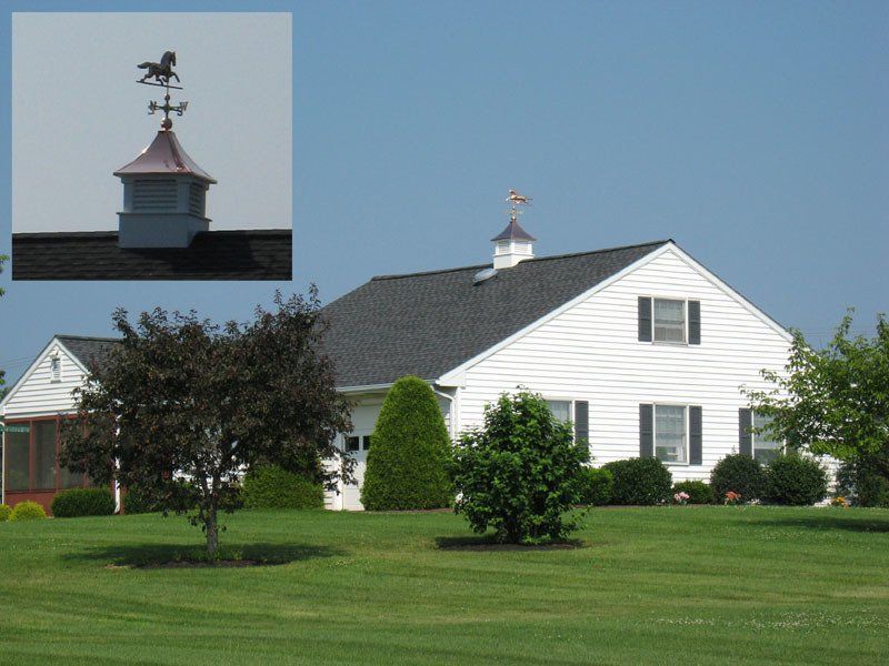 A white house with a weather vane on top of it