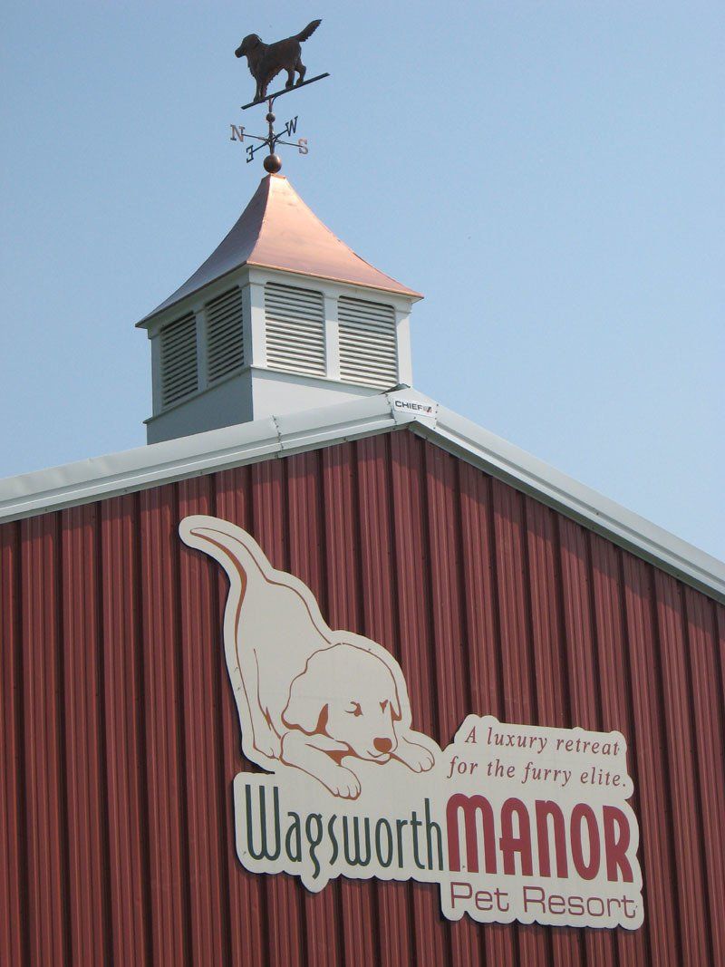 A weather vane on top of a building that says wagsworth manor pet resort