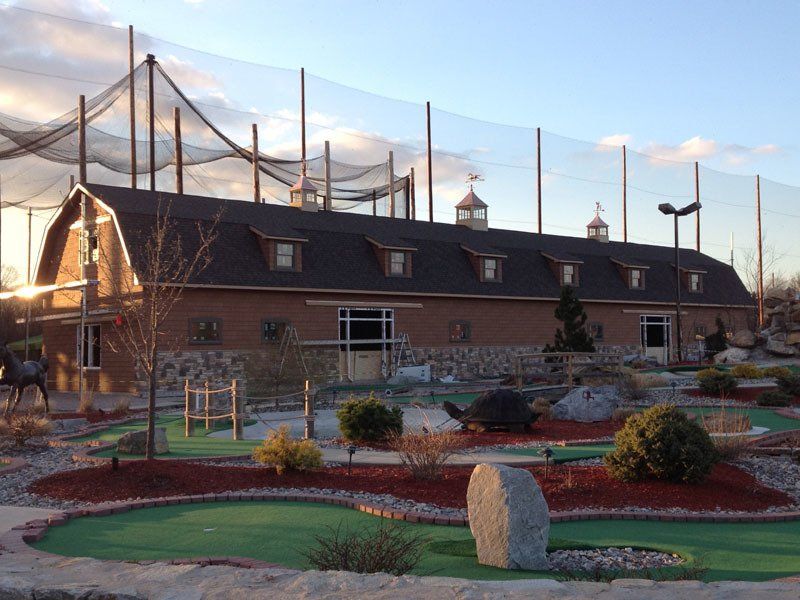 A small golf course in front of a large barn