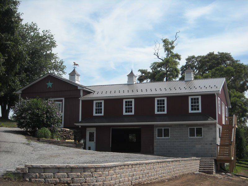 A large red barn with a brick wall in front of it
