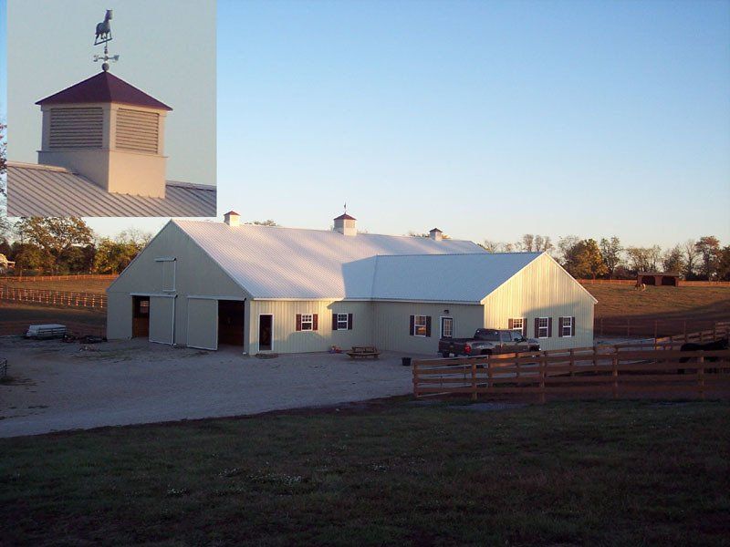 A white barn with a weather vane on top of it