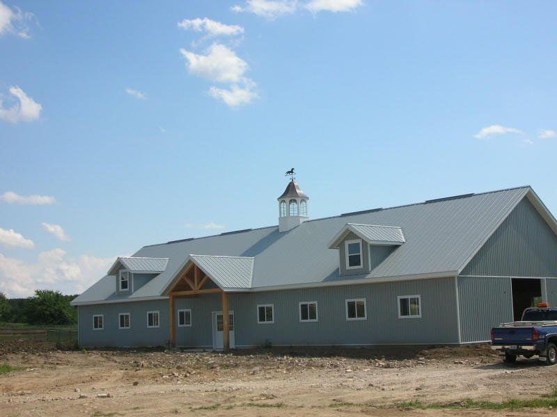 A large barn with a blue truck parked in front of it