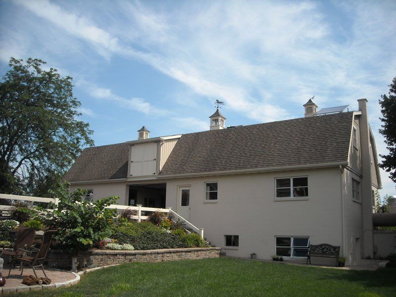 A white house with a brown roof and a white fence