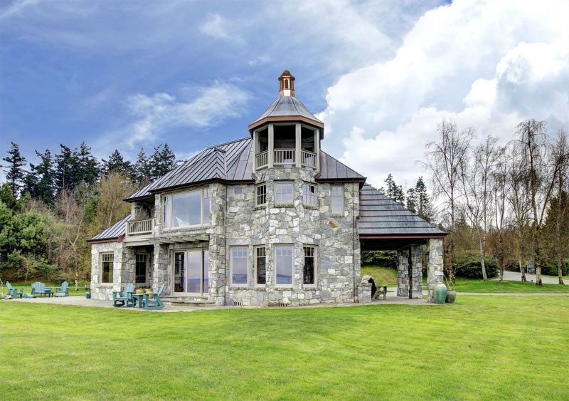 A large stone house is sitting on top of a lush green field.