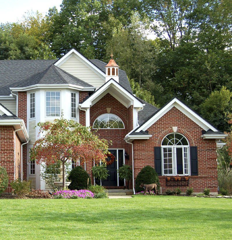 A large brick house with a large lawn in front of it