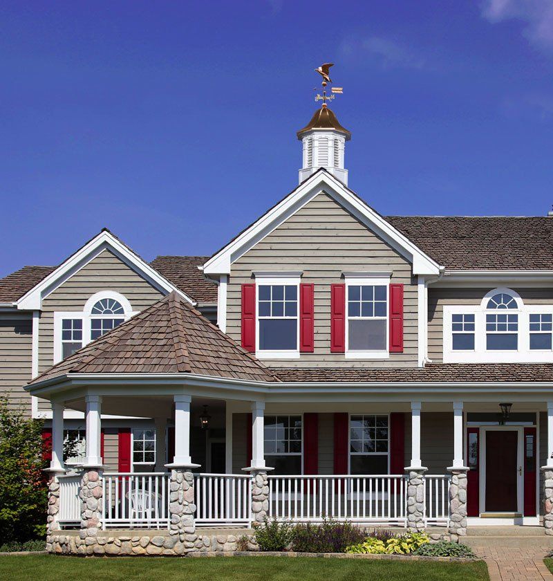 A large house with red shutters and a weather vane on top
