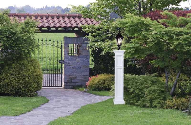 a stone walkway leading to a gate with a lamp post in front of it