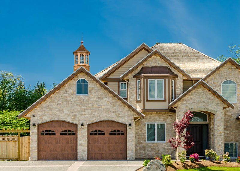 A large house with three garage doors and a cupola on top of it.
