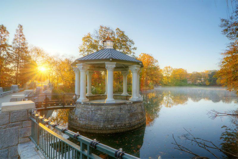 There is a gazebo in the middle of a lake surrounded by trees.