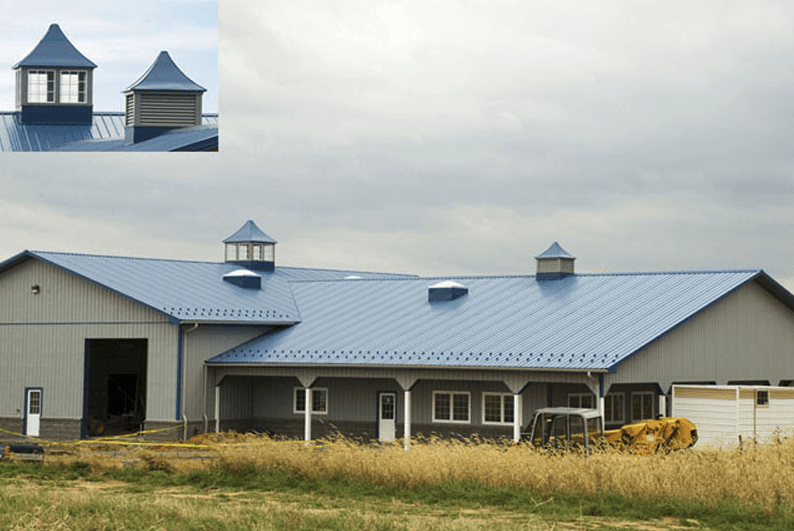 A large building with a blue roof is in a field