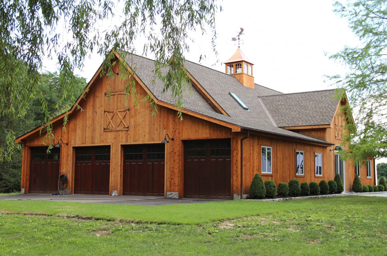 A large wooden barn with a cupola on top of it