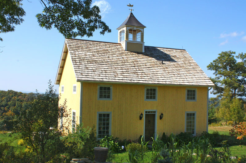 A yellow building with a weather vane on top of it