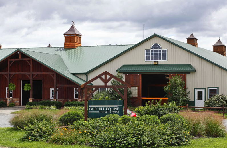 A large barn with a green roof and a sign in front