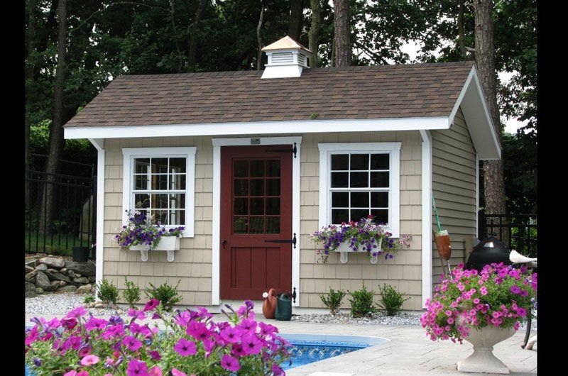 A small house with purple flowers in front of it
