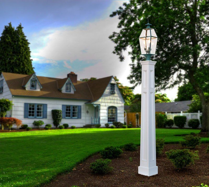 a white pole with a lamp on top of it in front of a house