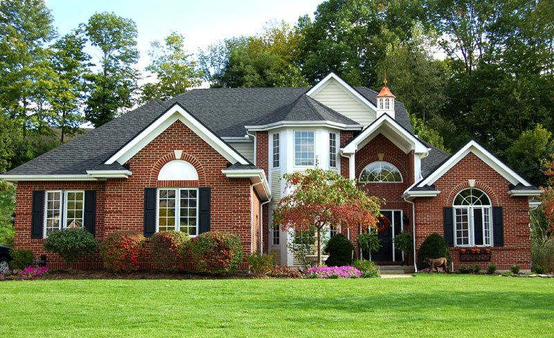 A large brick house with a lush green lawn in front of it