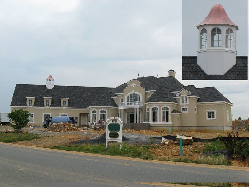 A large house with a copper roof is under construction