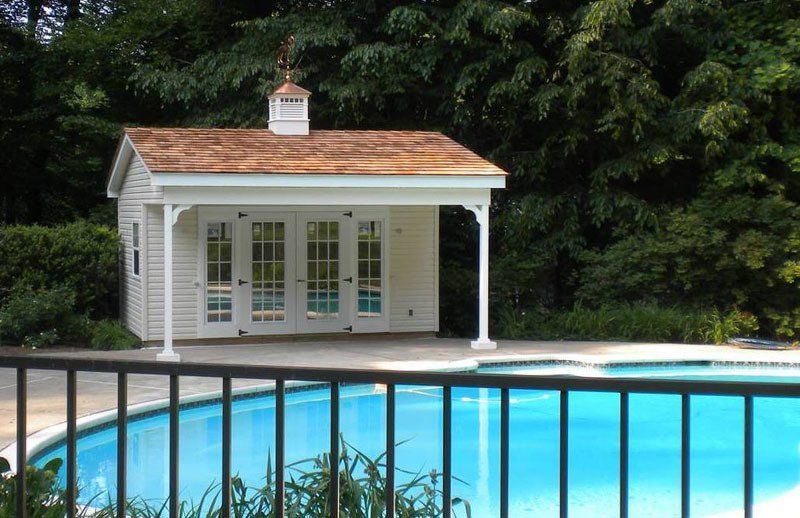 A white house is sitting next to a swimming pool.
