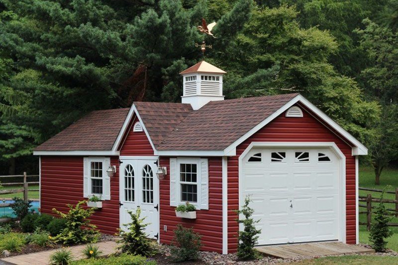 a red and white garage with a weather vane on top