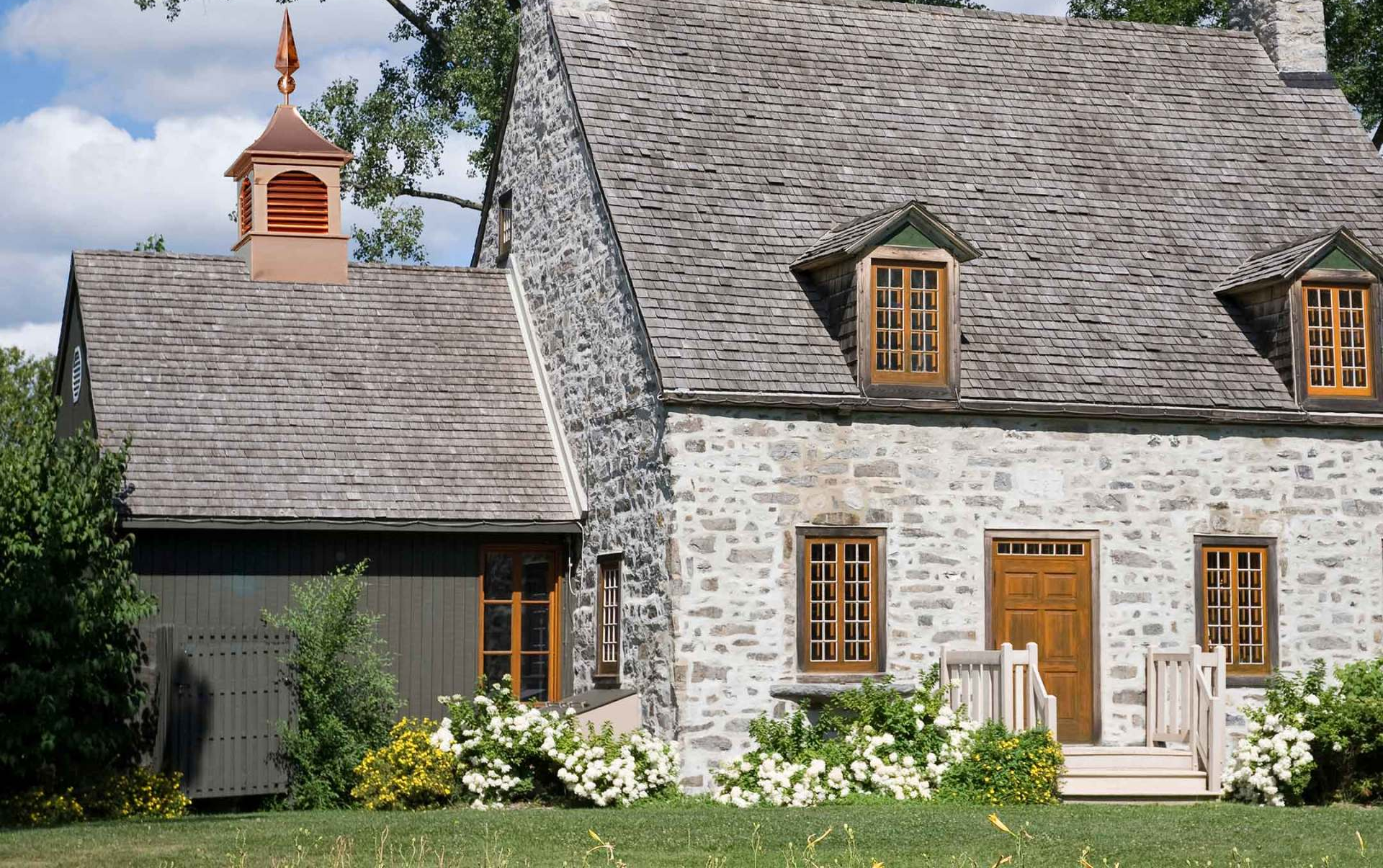 a stone house with a roof that has shingles on it