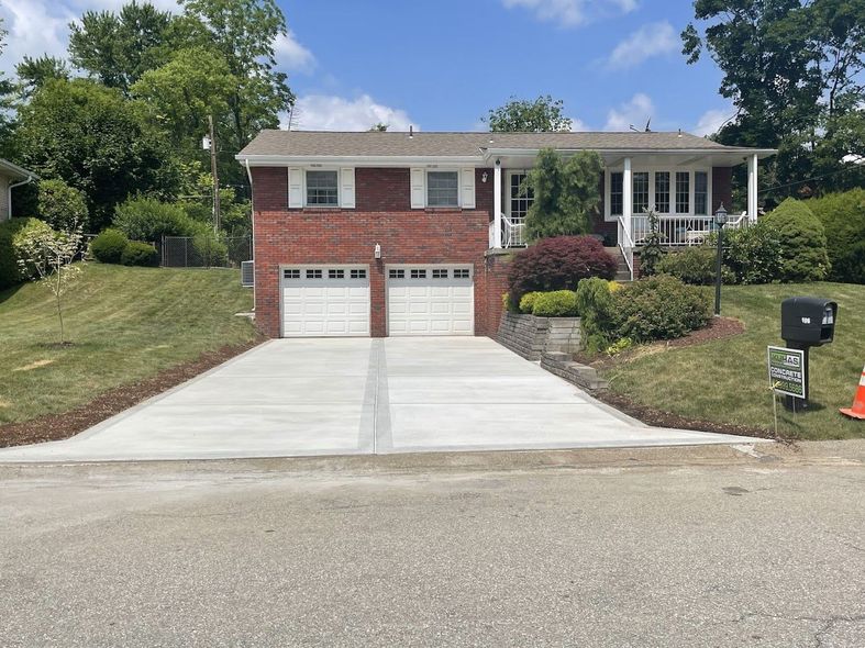 A brick house with a concrete driveway in front of it.