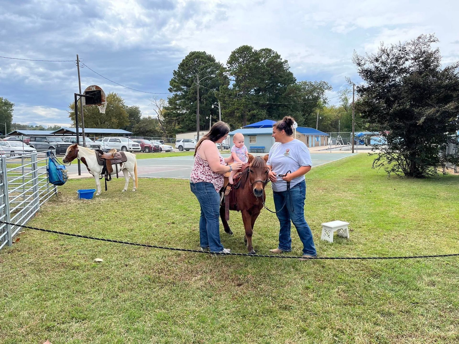 People with a child ride a pony at an outdoor event | pony rides
