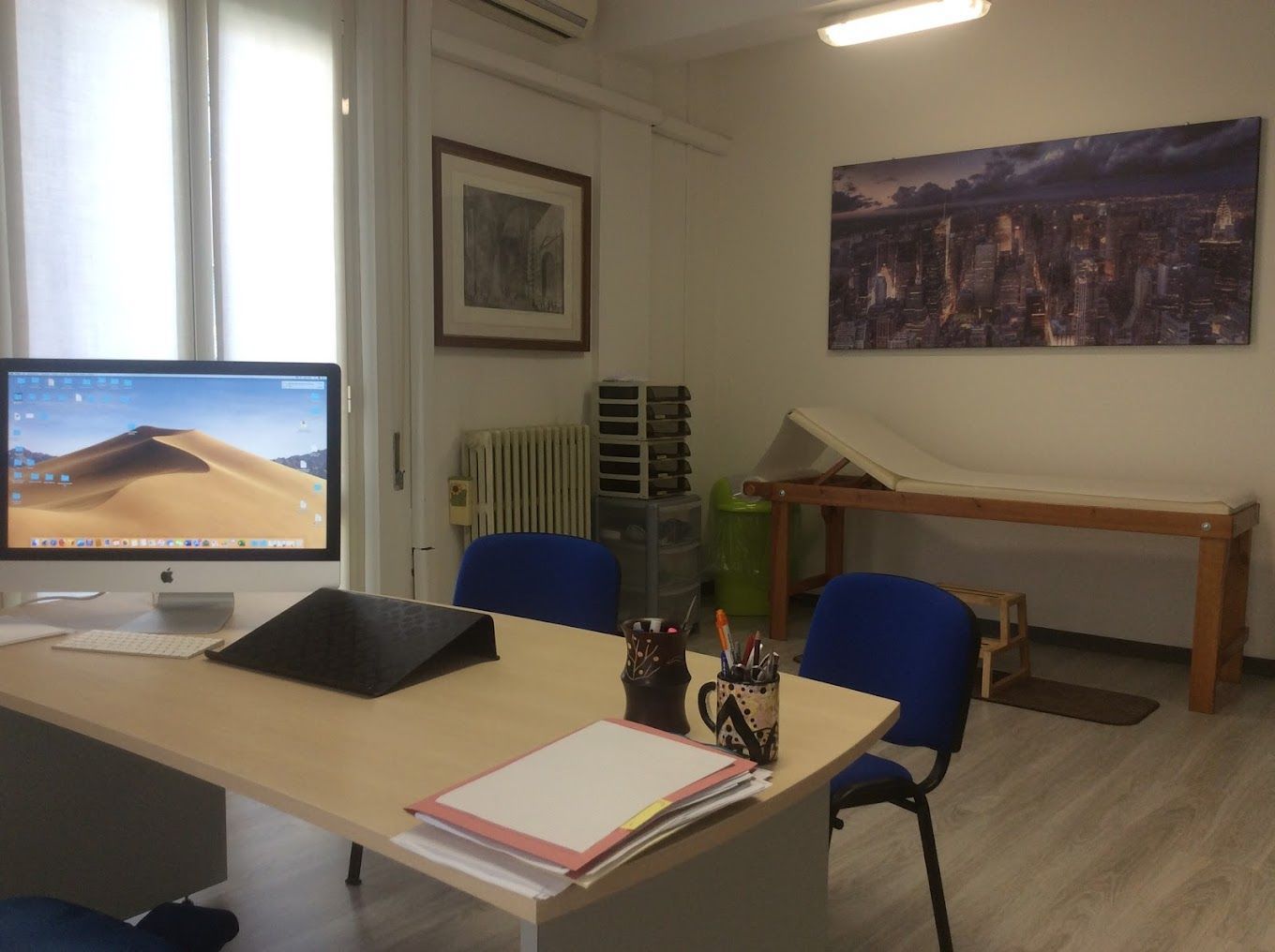 una scrivania con un computer e una sedia blu in una stanza