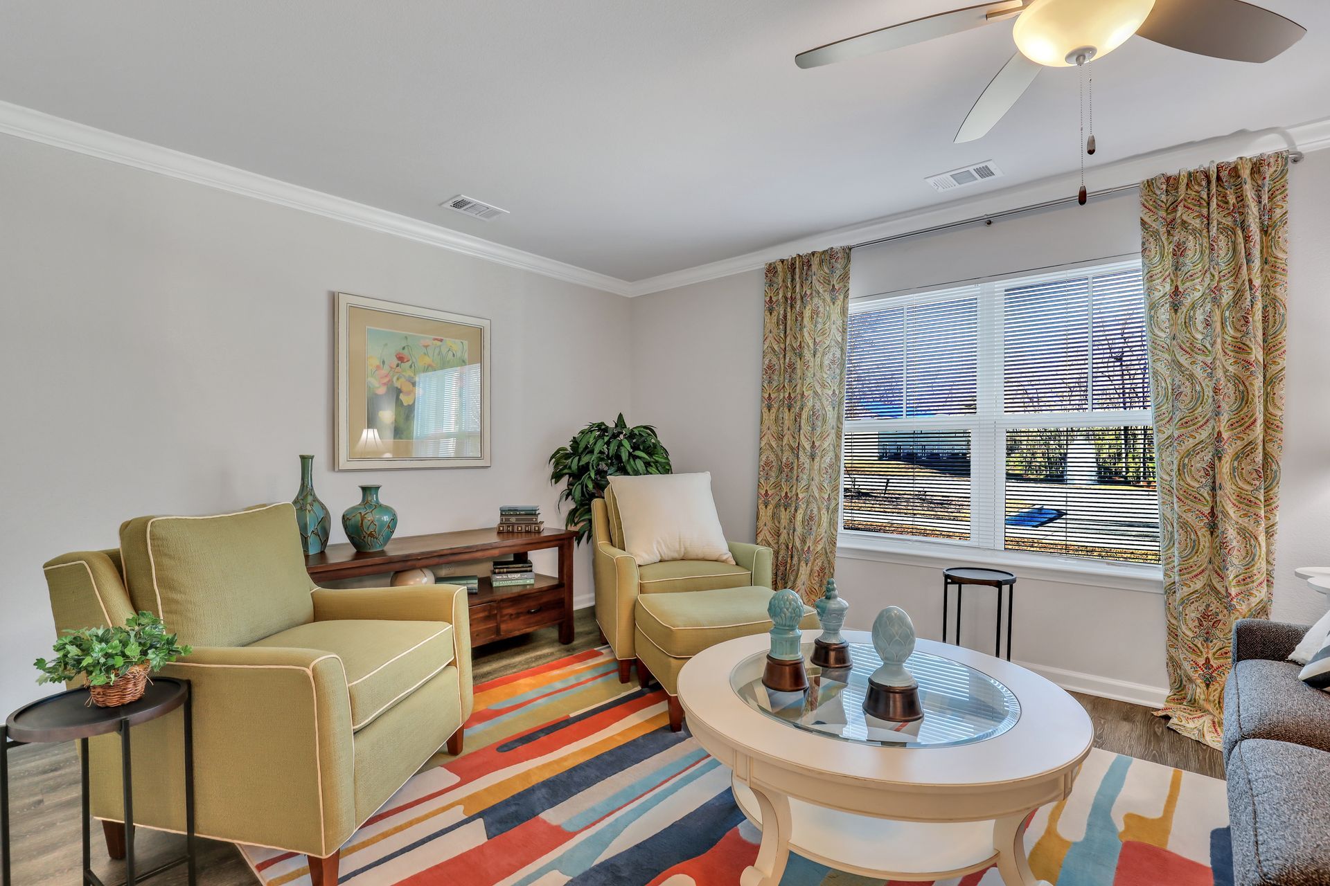 A living room with two chairs , a coffee table , and a ceiling fan.