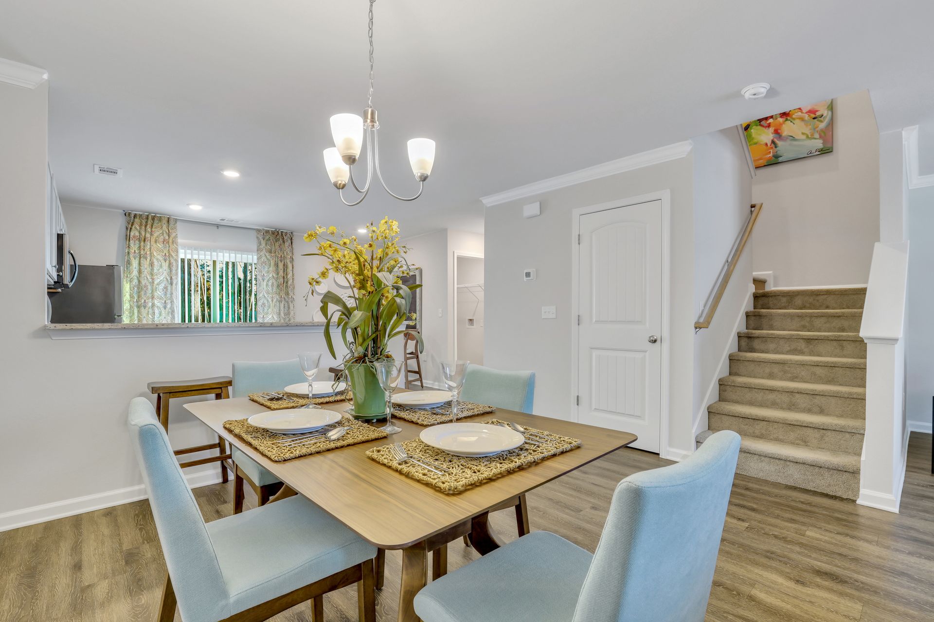 A dining room with a table and chairs and stairs.
