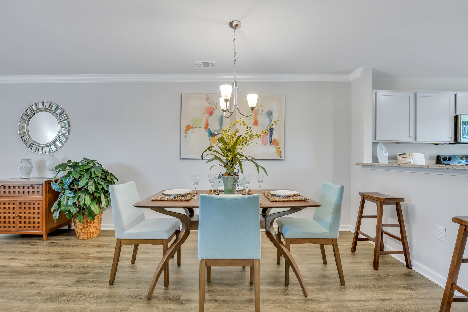A dining room with a table and chairs and a mirror on the wall.