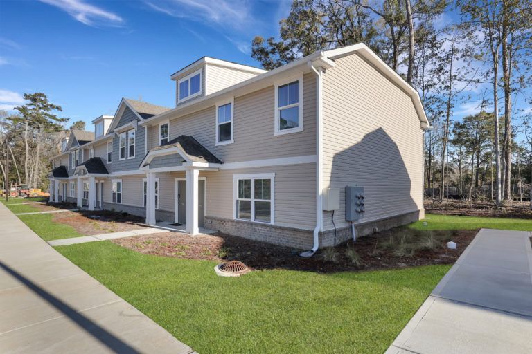 A row of houses sitting next to each other on a lush green lawn.