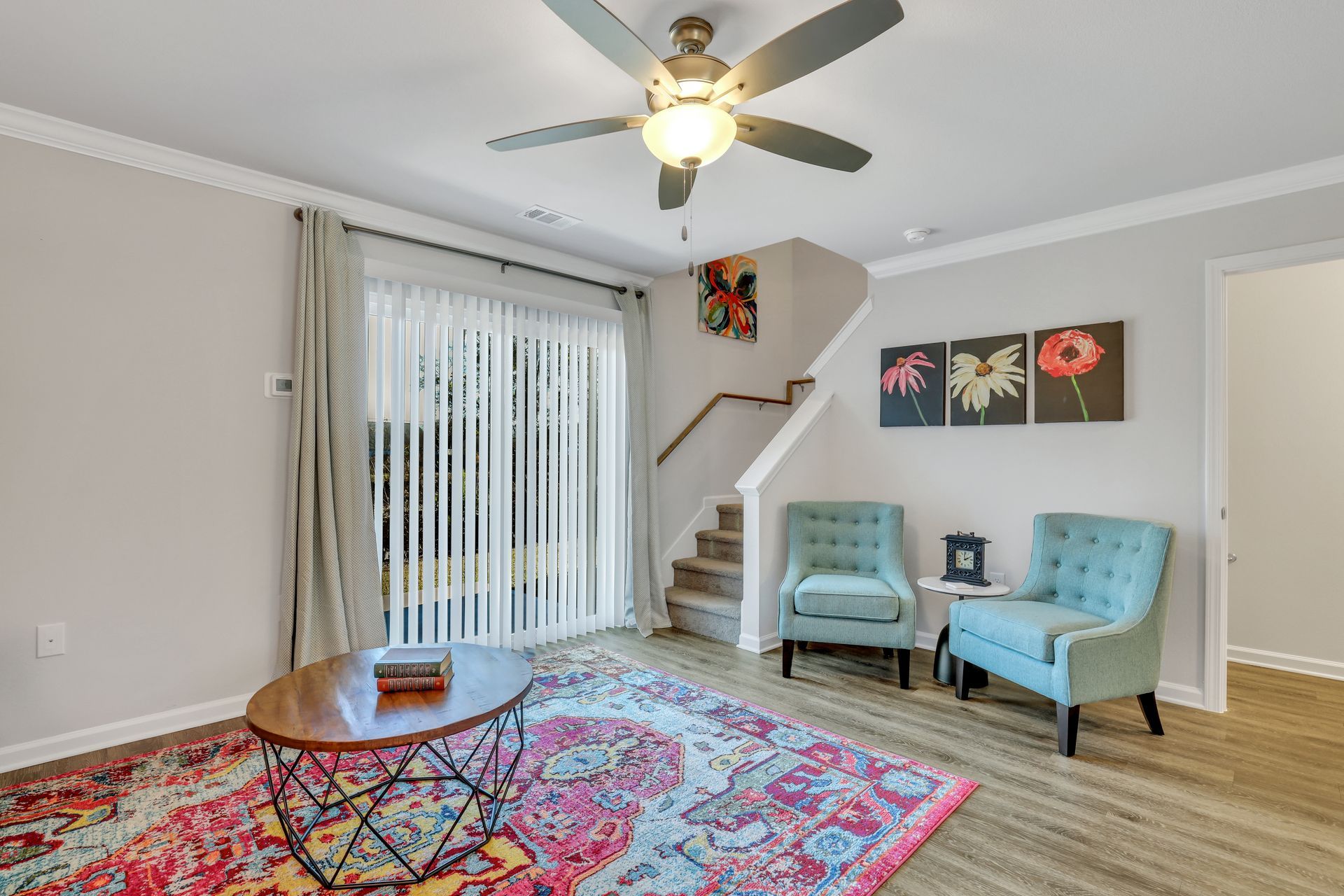 A living room with two chairs , a coffee table , and a ceiling fan.