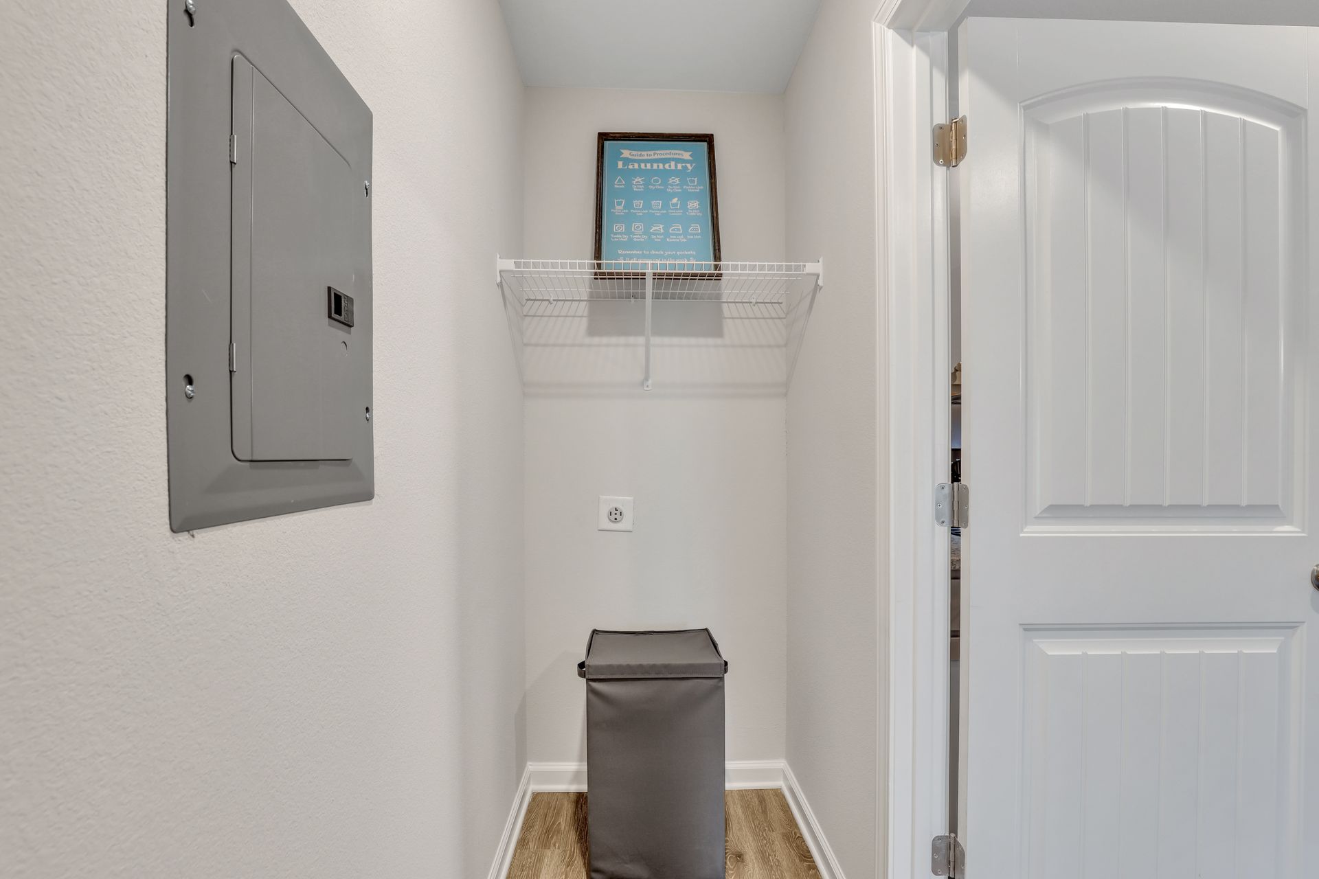 There is a laundry room with a laundry basket and a picture on the wall.