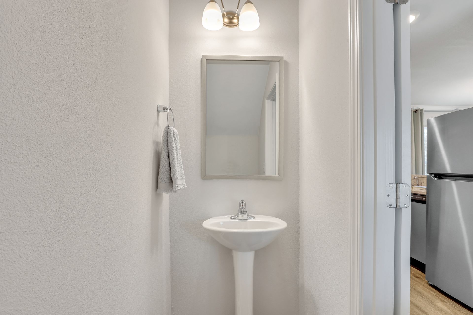 A bathroom with a sink , mirror and refrigerator.