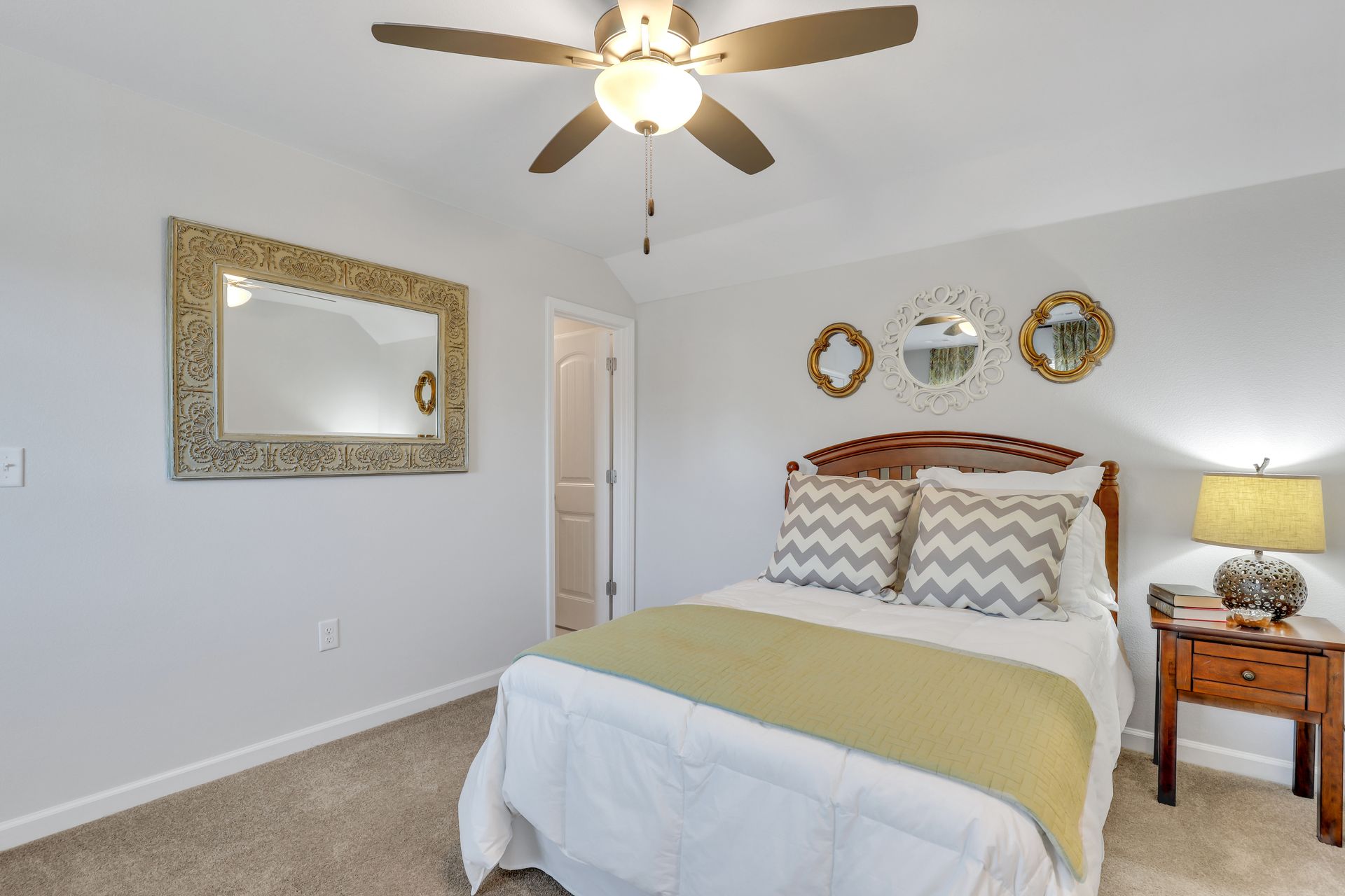 A bedroom with a bed , nightstand , mirror and ceiling fan.