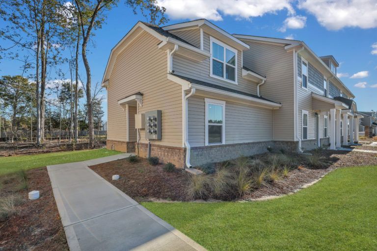 A house with a walkway leading to it and a lot of windows.