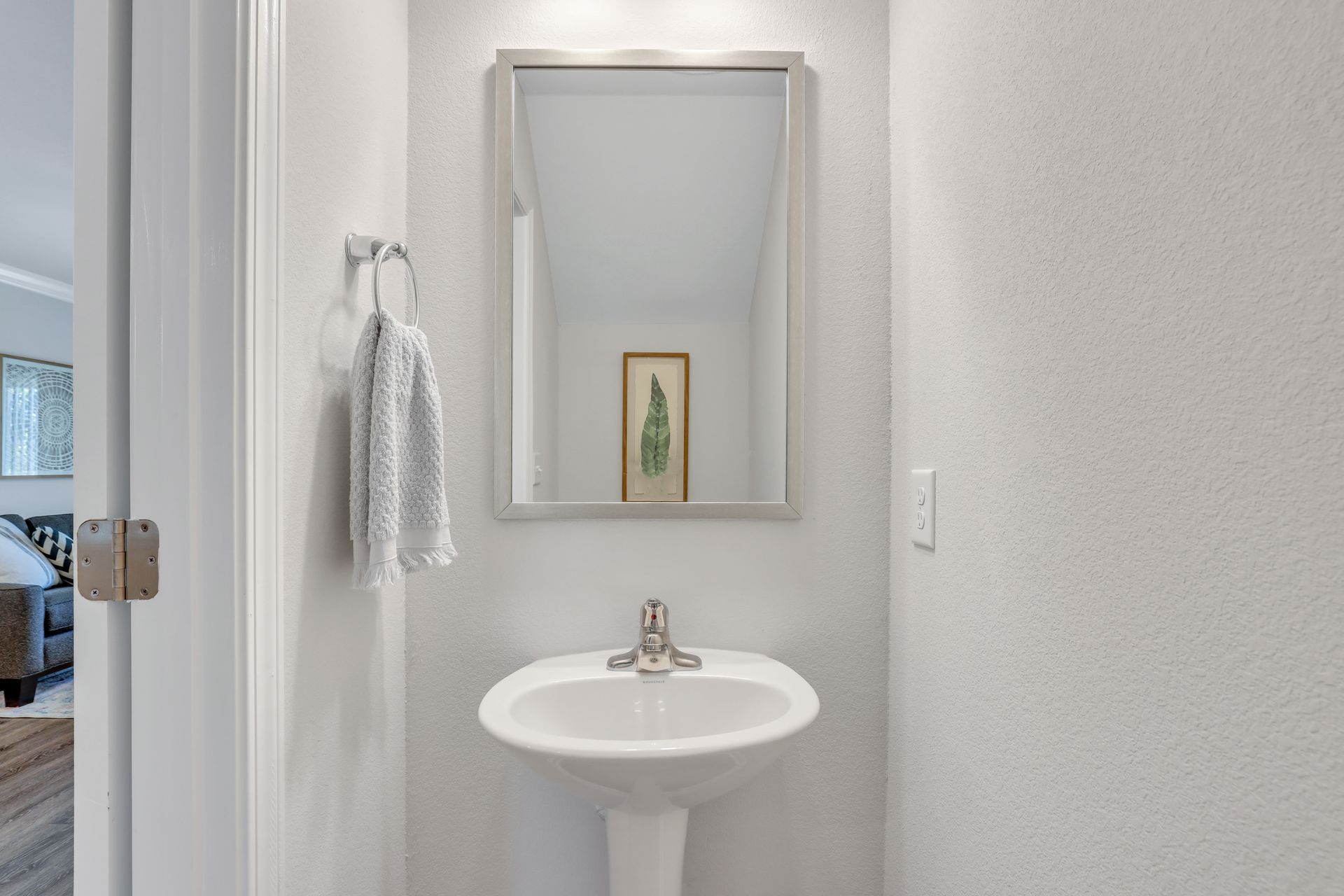 A bathroom with a sink , mirror and towel rack.