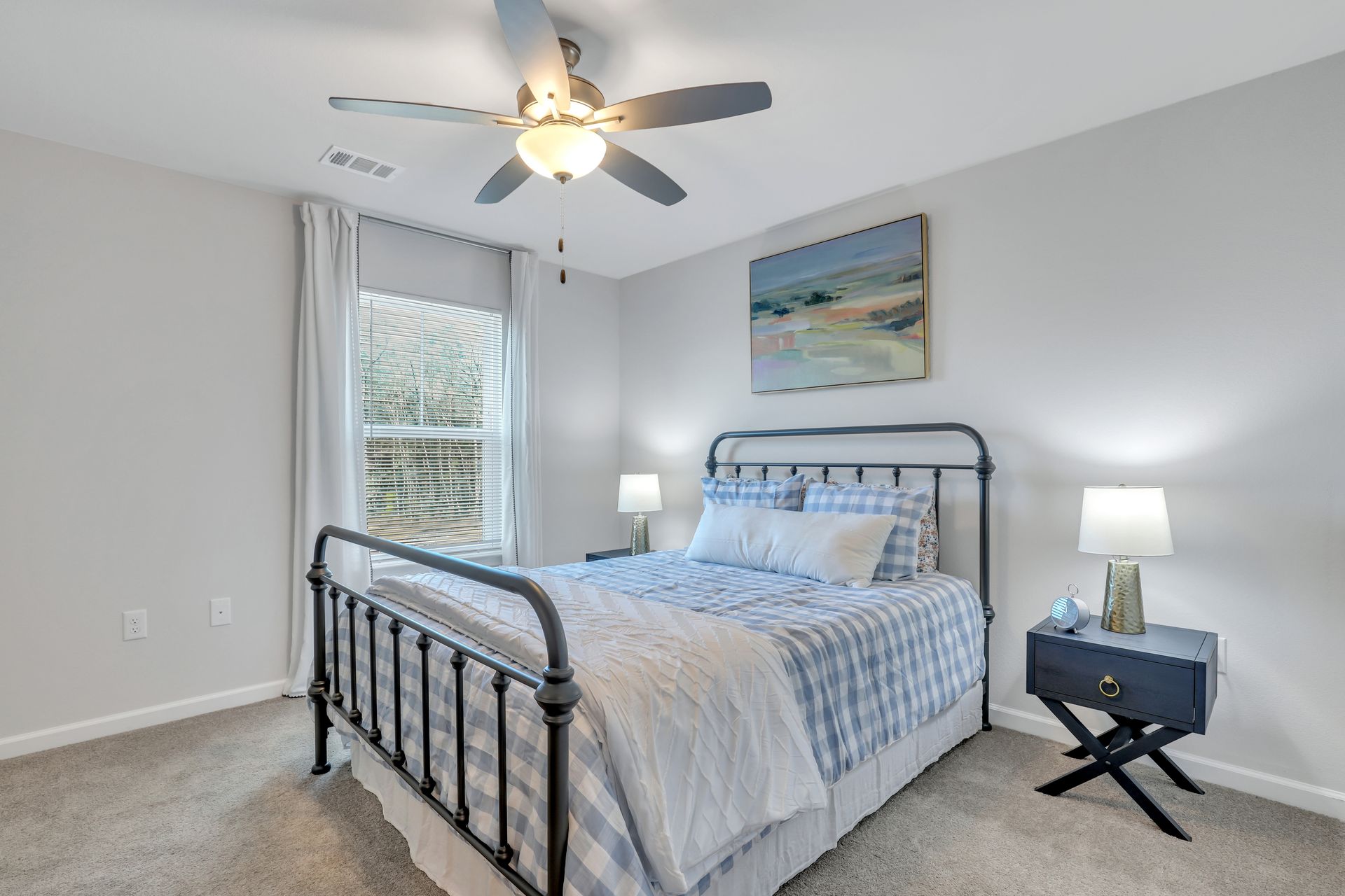 A bedroom with a bed , nightstand , lamps and a ceiling fan.
