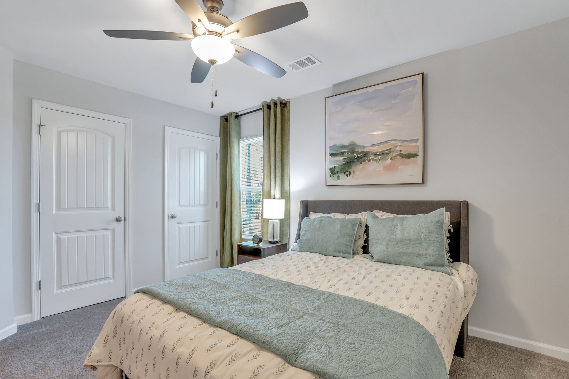 A bedroom with a bed and a ceiling fan.