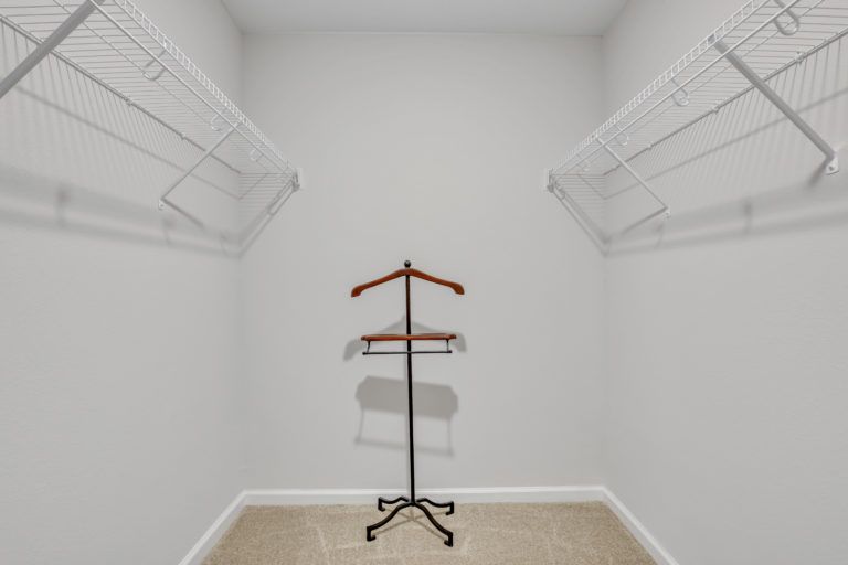 An empty walk in closet with a clothes rack and a hanger.